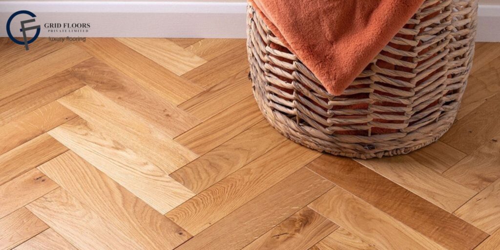 A basket rests on engineered hardwood flooring, topped with a vibrant orange towel.